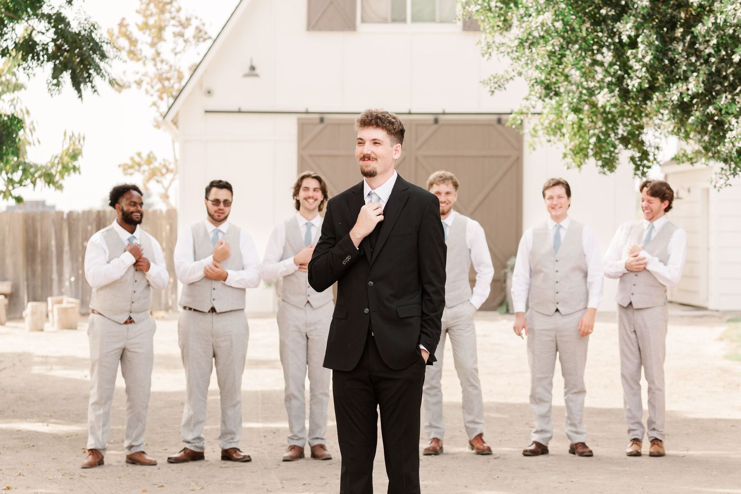 Wedding party members pose outdoors in coordinated gray and black attire.