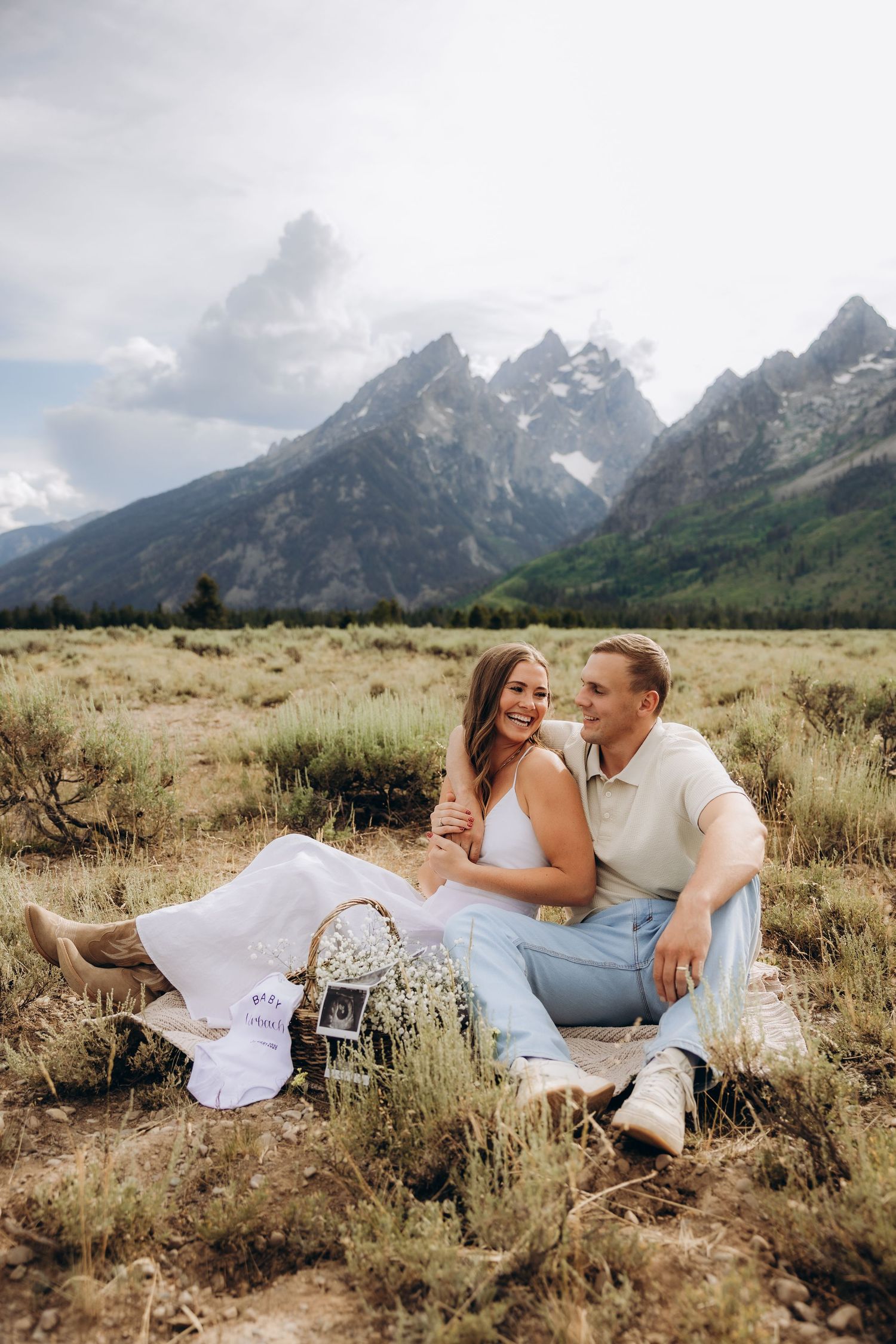 Intimate picnic scene in mountain meadow with dramatic Teton peaks rising in background.