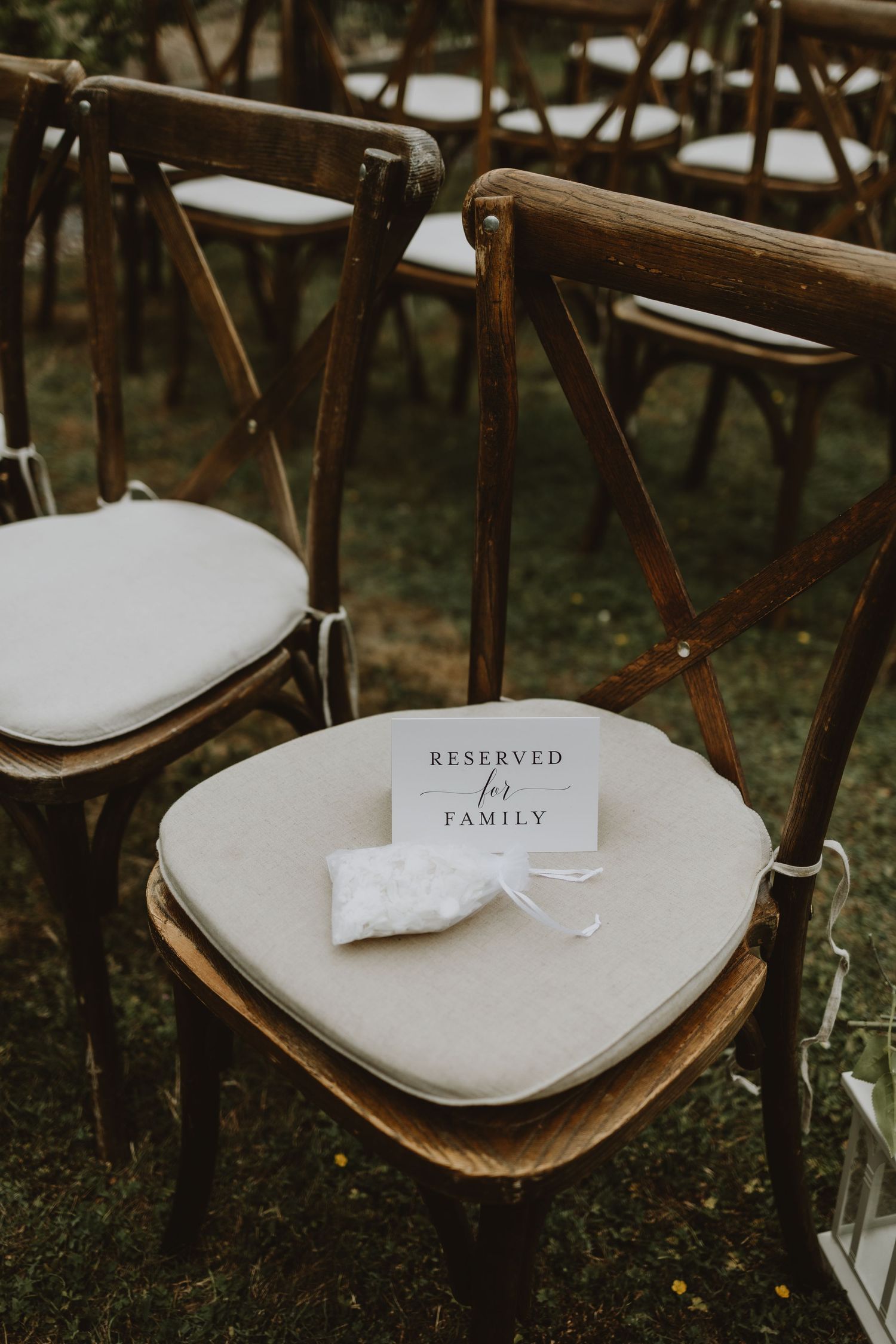 Rustic wooden wedding welcome sign decorated with white flowers and greenery under a natural garden arch.