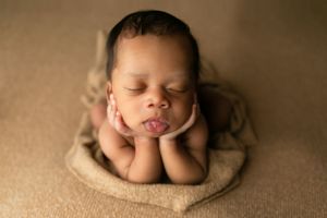 Orlando FL Newborn Photography 21 Moments Photography newborn boy on brown backdrop holding his hands on his chin