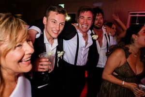 Large group of people celebrating at a party or reception with drinks and dancing.