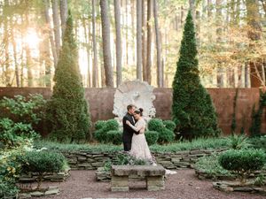 A beautiful outdoor wedding ceremony setup in a wooded area with stone seating and lush greenery.