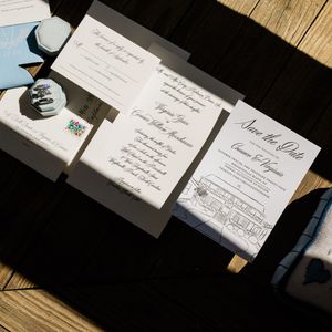 Elegant wedding invitation suite with classic calligraphy displayed on wooden surface in natural lighting.