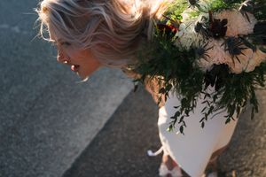 A wedding bouquet featuring white flowers and greenery with warm natural sunlight illuminating delicate details.