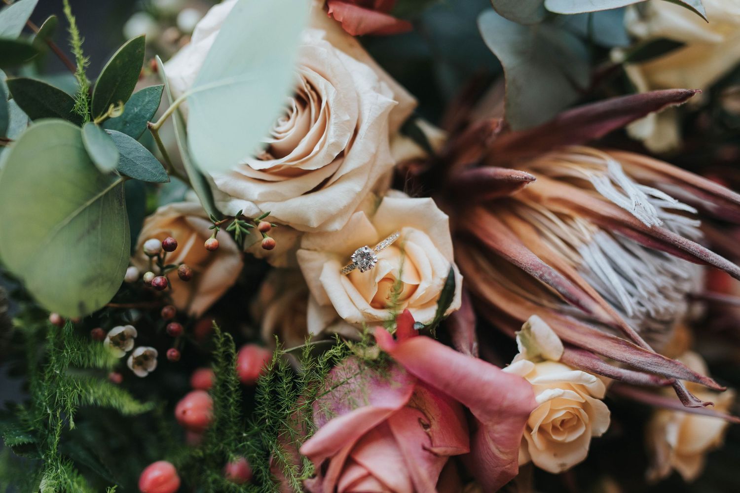 A collection of blush pink roses and mixed flowers with green foliage arranged in a romantic floral design.