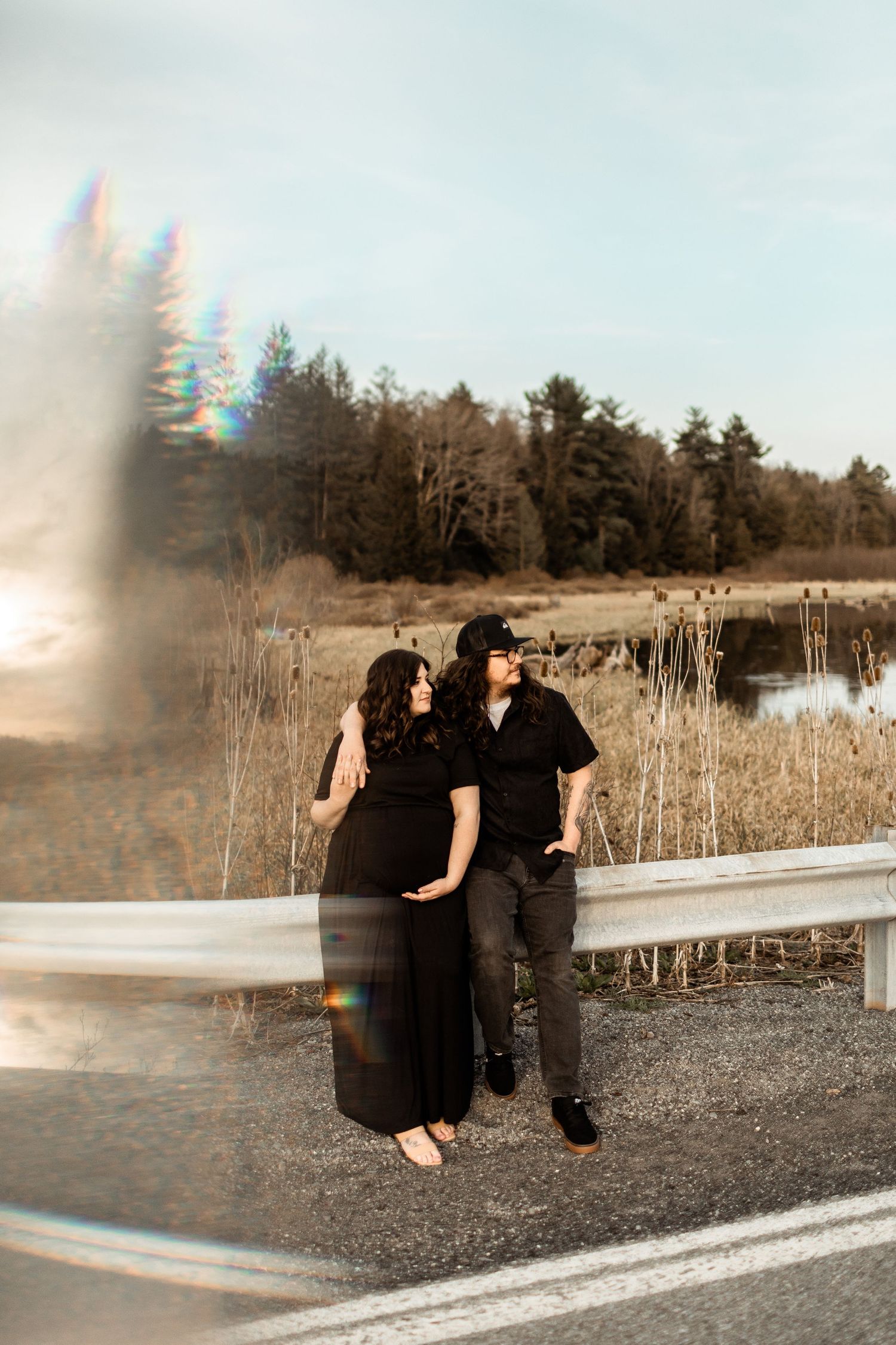 A joyful family sharing a tender moment together while sitting in a grassy field with dried plants on a sunny day.