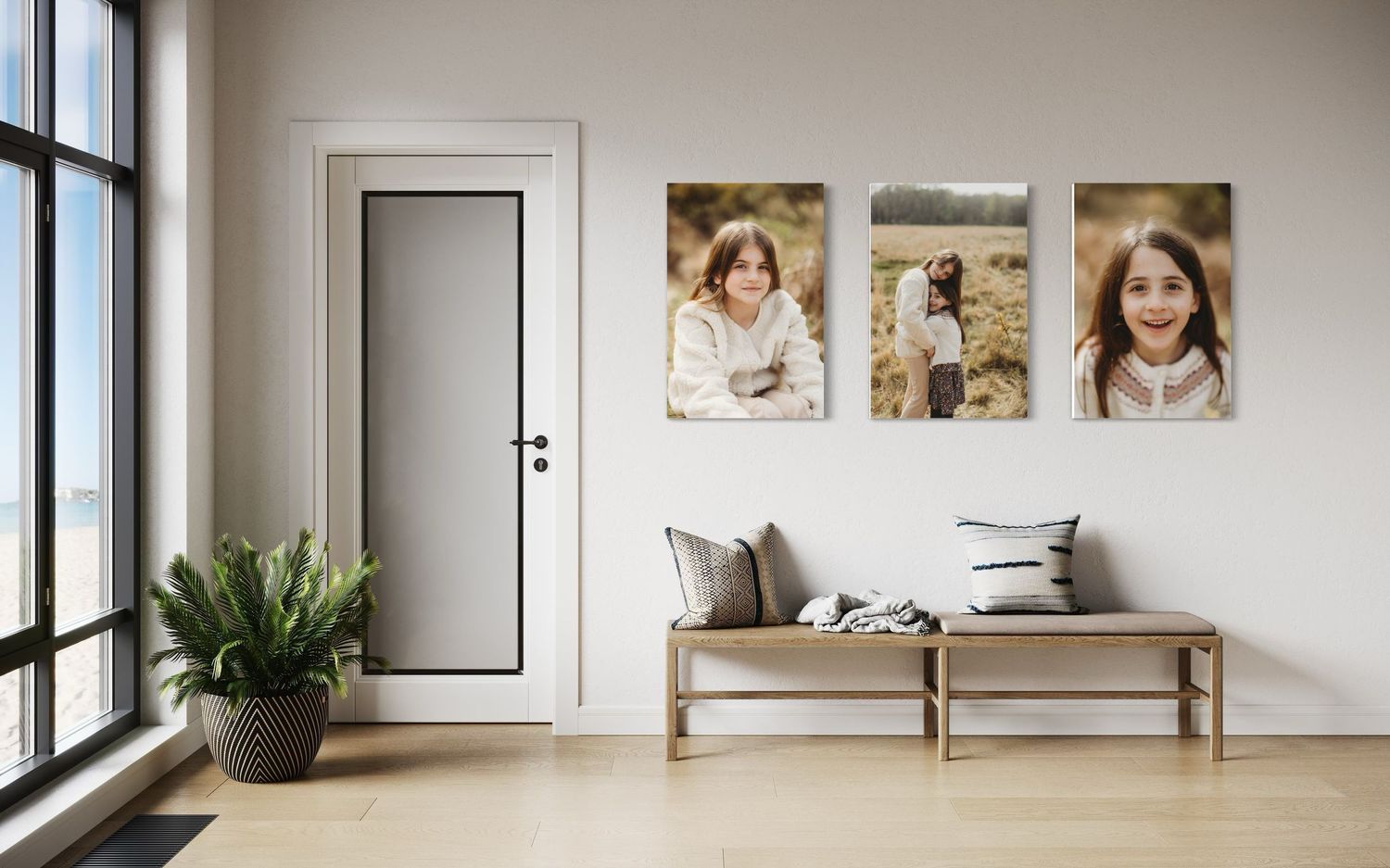 A modern minimalist entryway with a wooden bench, portrait photos on white walls, and a potted plant by the window.
