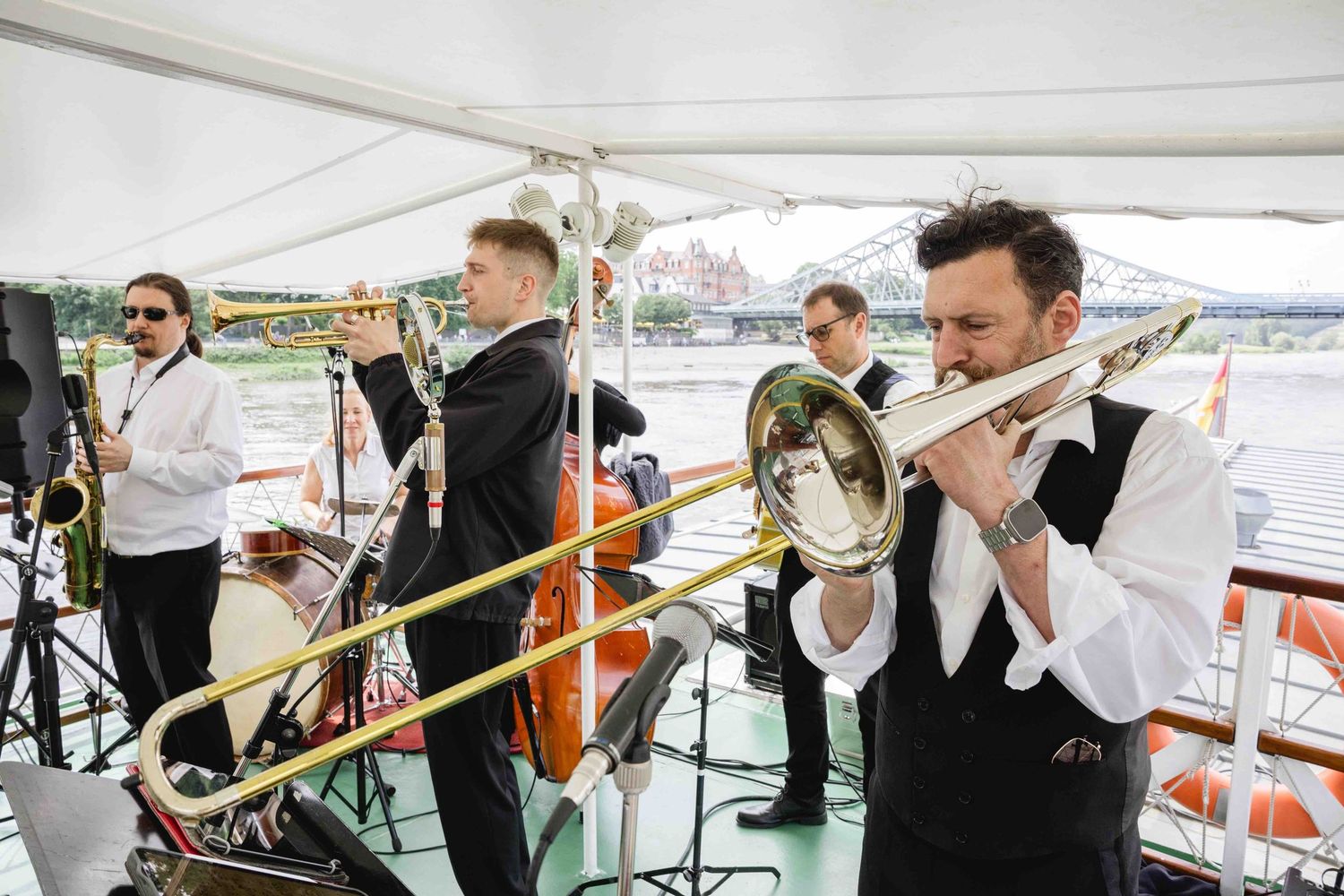 Musicians in formal attire perform on brass instruments in various poses.