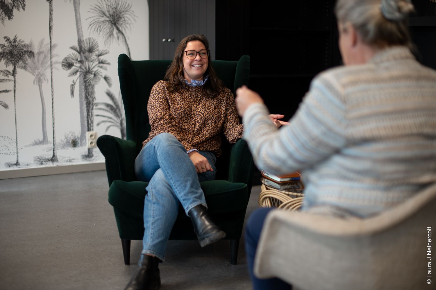 Two people engage in collaborative discussion around a workspace with creative materials.