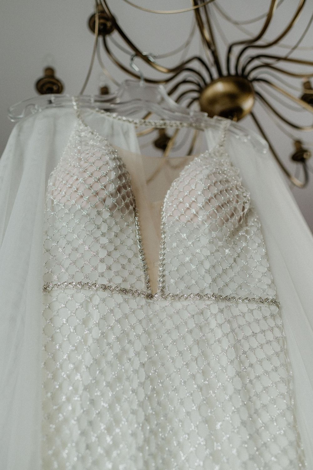 Wedding dress bodice detail showing intricate beaded pearl pattern on white fabric.