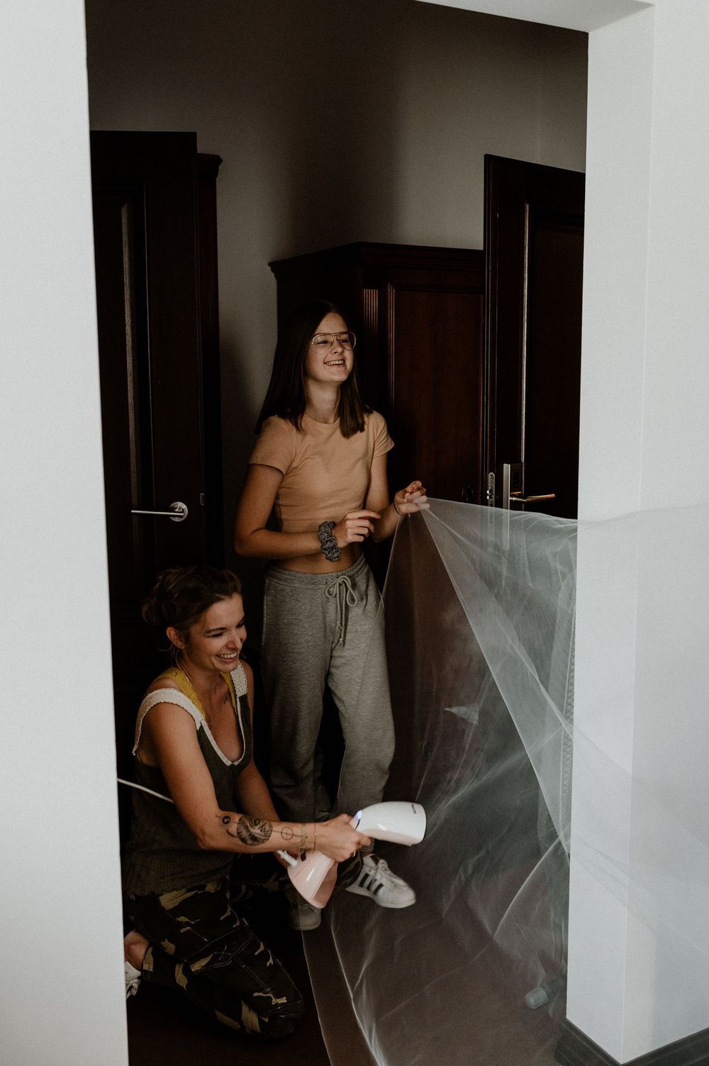People preparing in a dimly lit room with white walls and doorways.