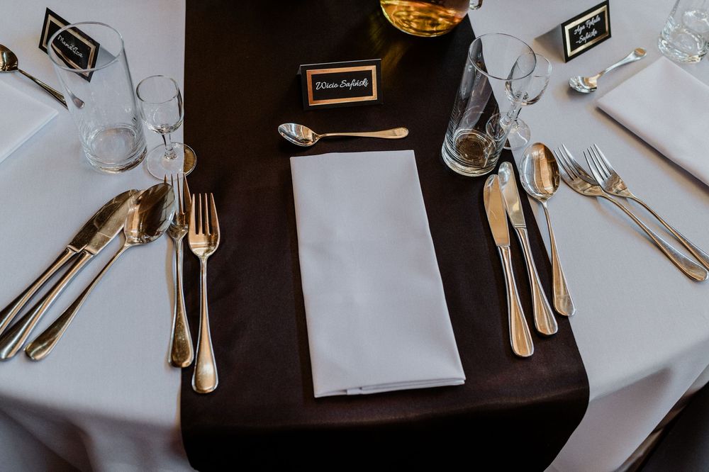 Elegant place setting with silverware and napkin on a black and white tablecloth.