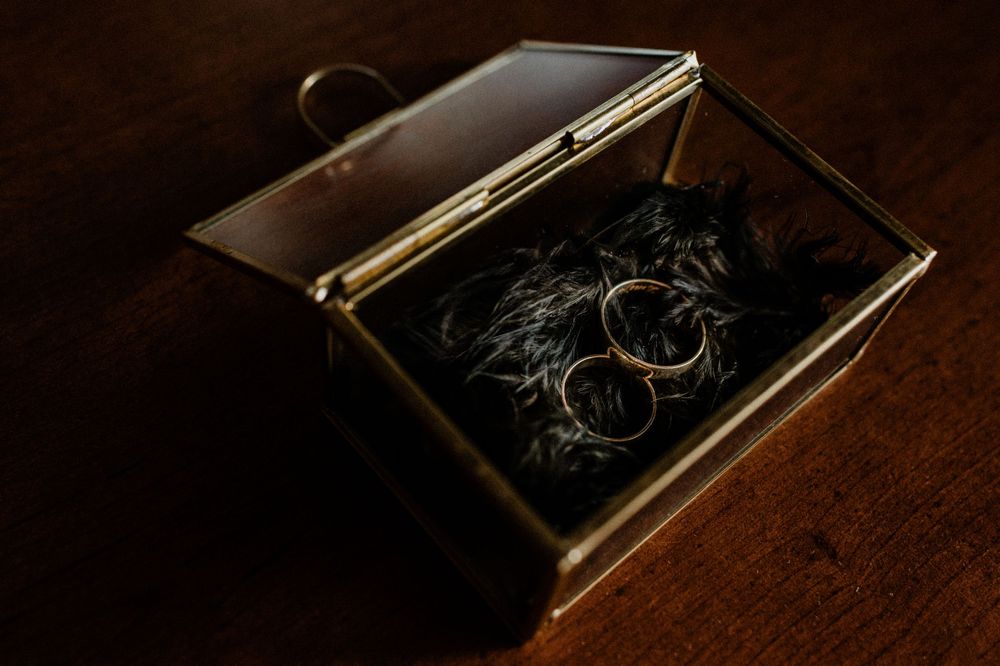 Artistic detail shots of wedding rings and jewelry in moody lighting.