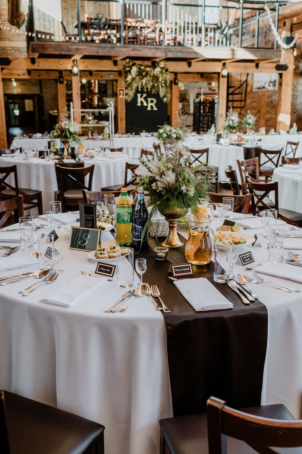 Wedding reception tables decorated with floral centerpieces and brown table runners.