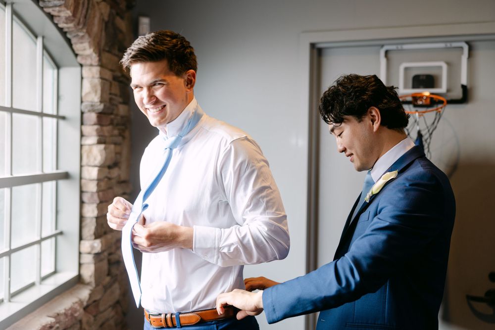 Wedding party getting ready in a bright room with natural light from large windows.