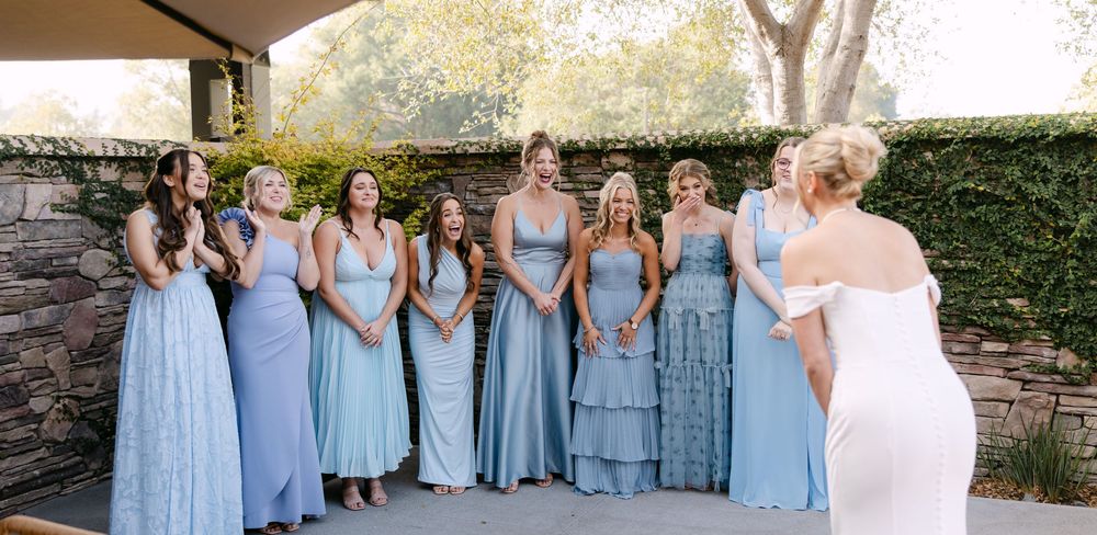 Wedding party in light blue bridesmaid dresses posed together outdoors.