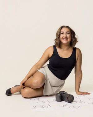 Person lying on floor with photography equipment in casual attire.