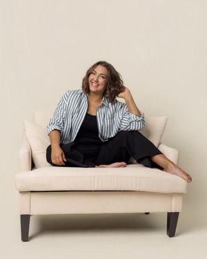 Person lounging on beige sofa wearing striped shirt and black outfit.