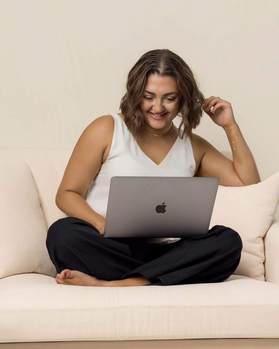 Person relaxing on white couch while working on MacBook laptop.