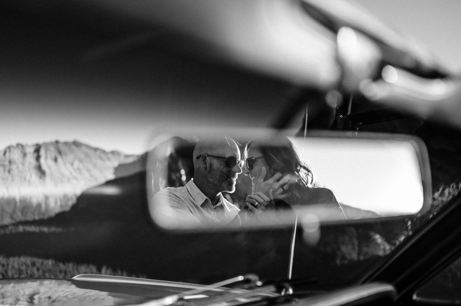Black and white panoramic sequence showing a car driving through a scenic mountain road with dramatic lighting.