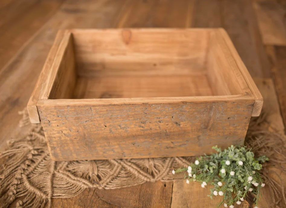Rustic wooden box with carved details and delicate white baby's breath flowers arranged on a warm wooden surface.