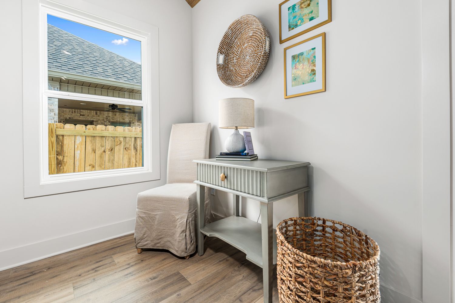 Bright white living space with coastal artwork and woven basket decor creates a serene atmosphere.