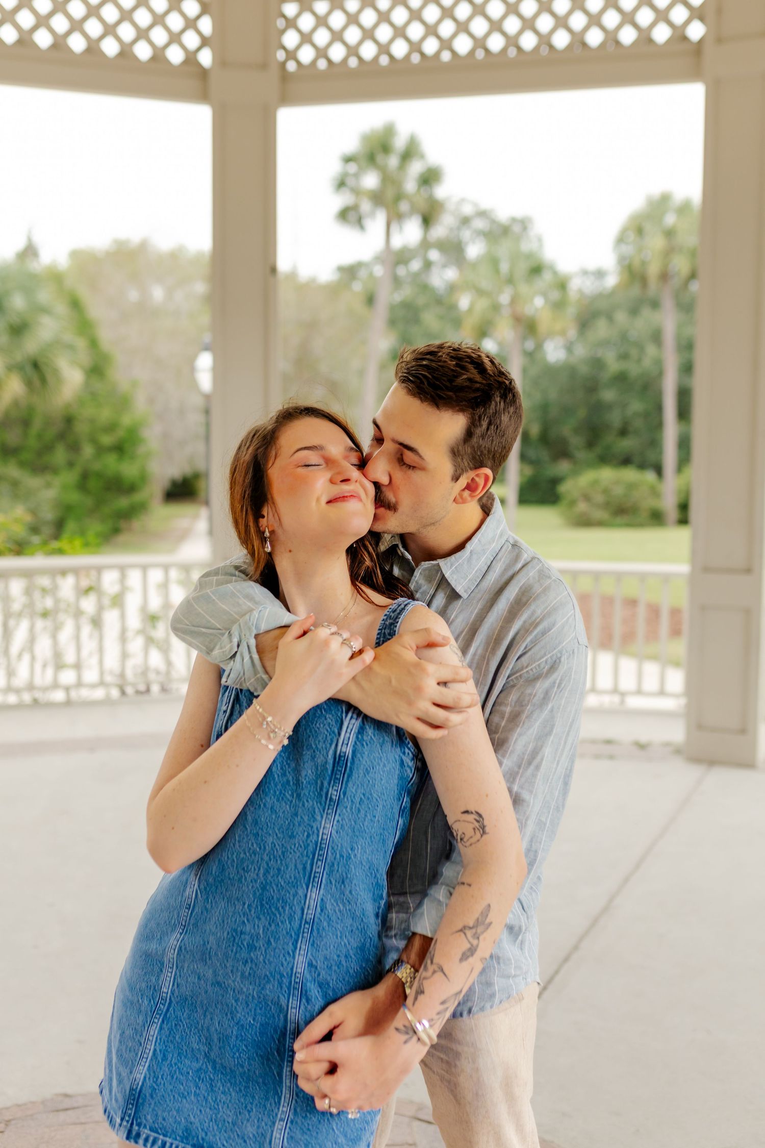 Romantic couple sharing intimate moments under covered porch during engagement session.