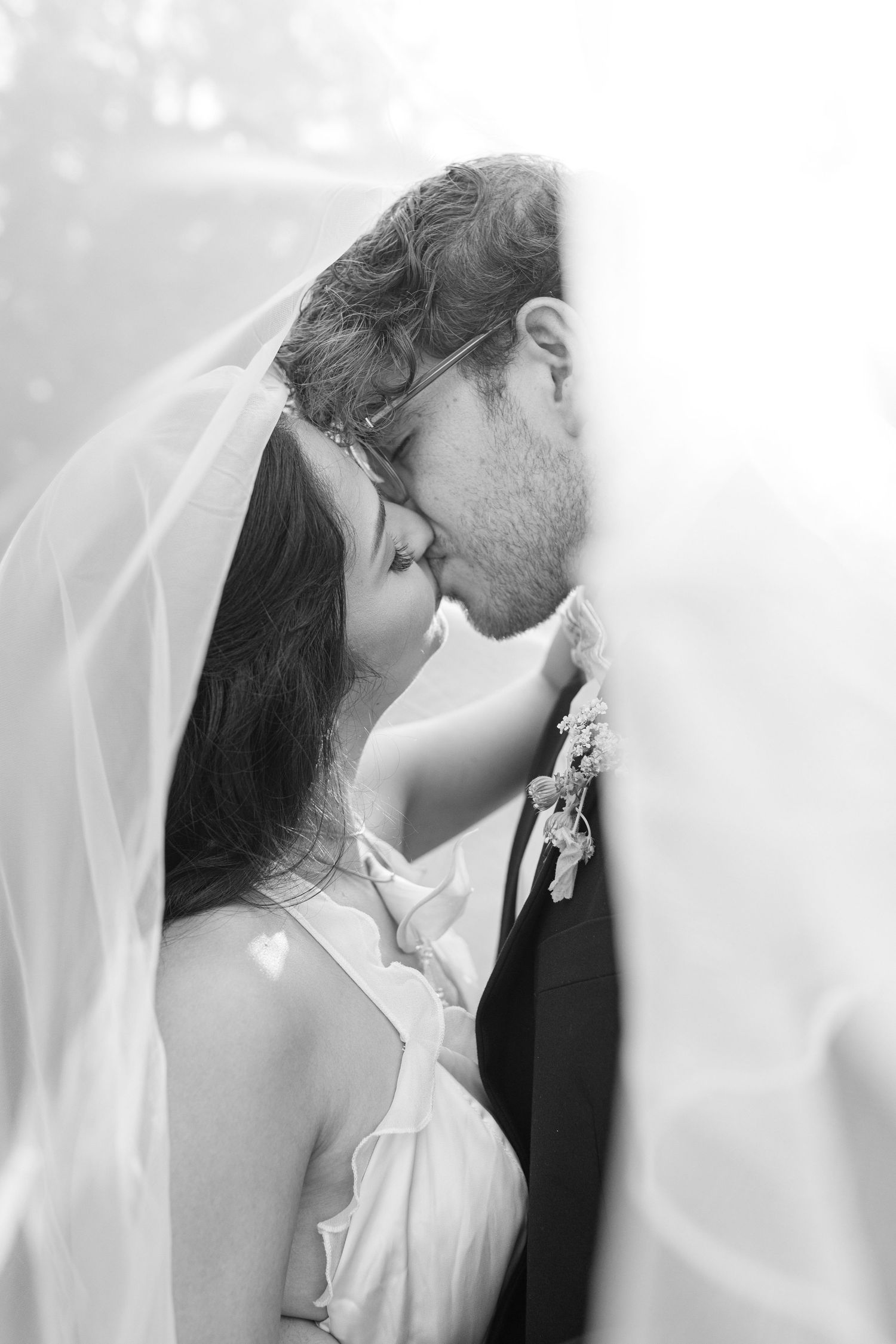A romantic black and white wedding photo series showing tender moments between newlyweds with flowing veil details.