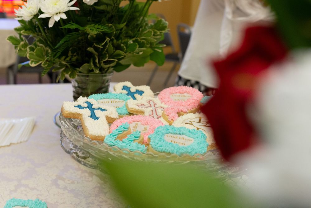 Pink white and blue cookies surrounded by foliage at baptism event session.