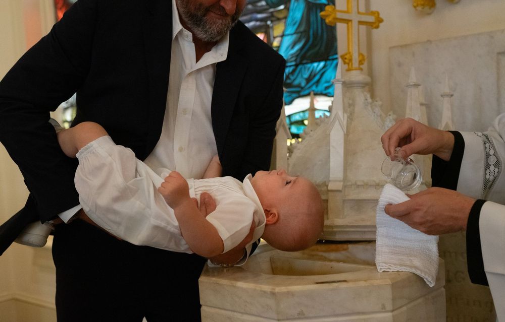 Child being held over baptismal bowl during an event session.