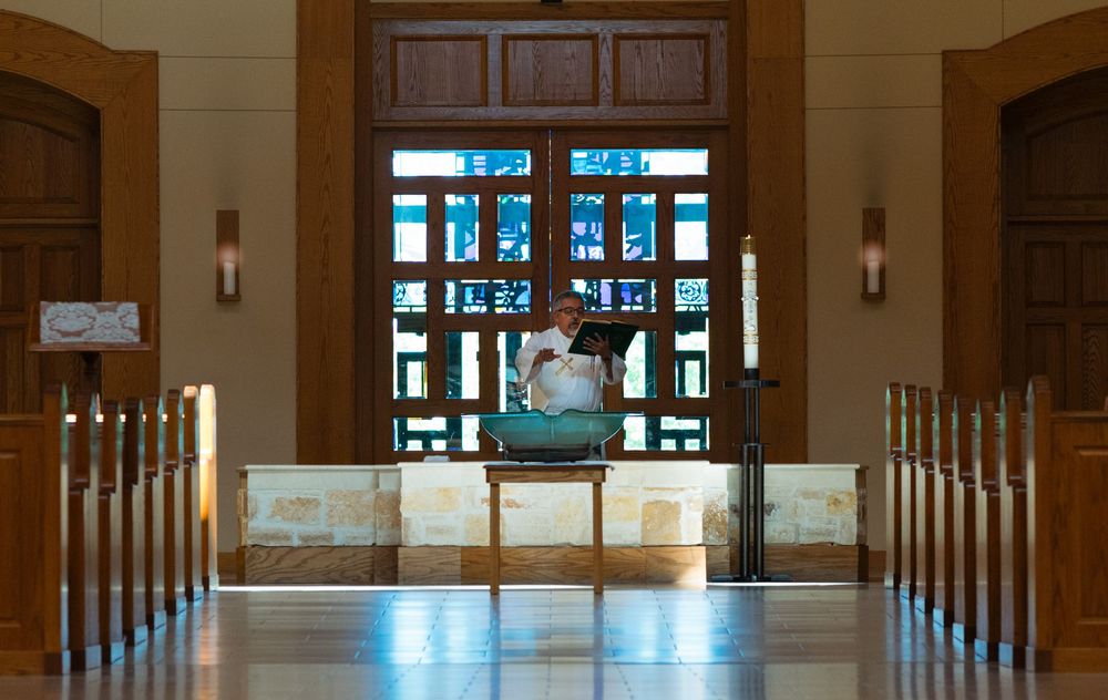 Priest blessing baptism water during baptism service during an event session.