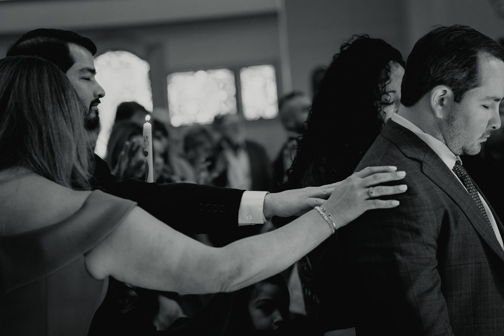 Hands on the person receiving a blessing during a baptism mass event session.