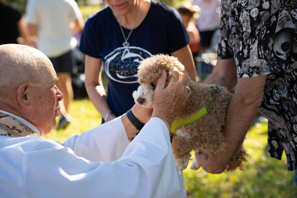 Priest holds on to dog being help up during the Blessing of the Pets at an event session in Bay City TX.