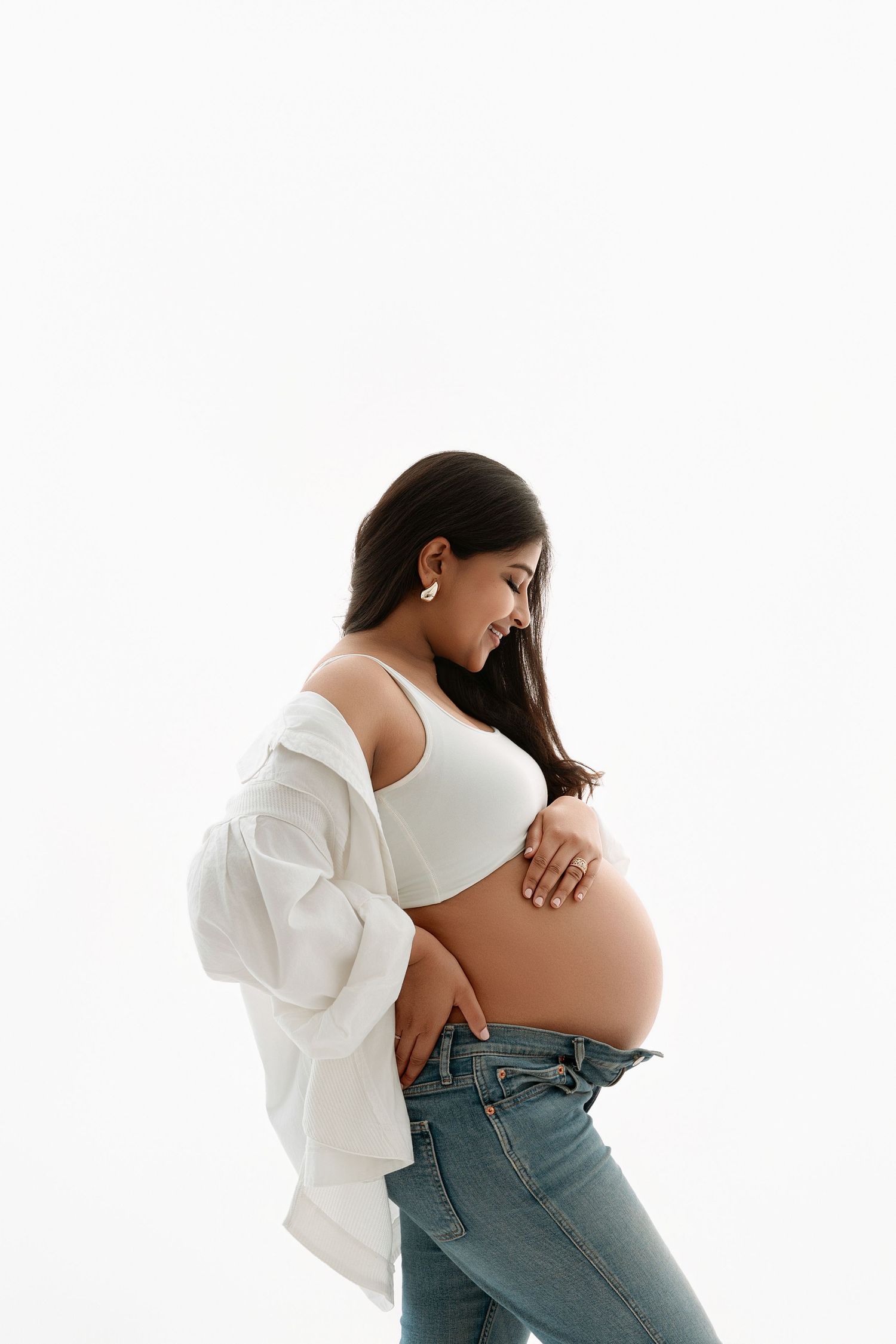 Woman in white shirt and jeans poses against white background in three artistic maternity photos. maternity photographer Paloma Schell
