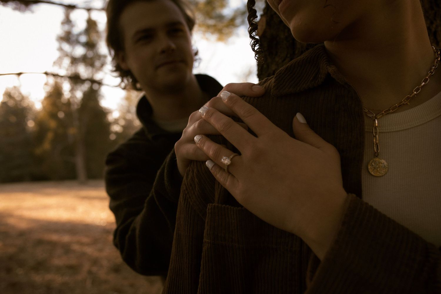 Someone holds a small dark dog against a warm sunset background in a natural outdoor setting.