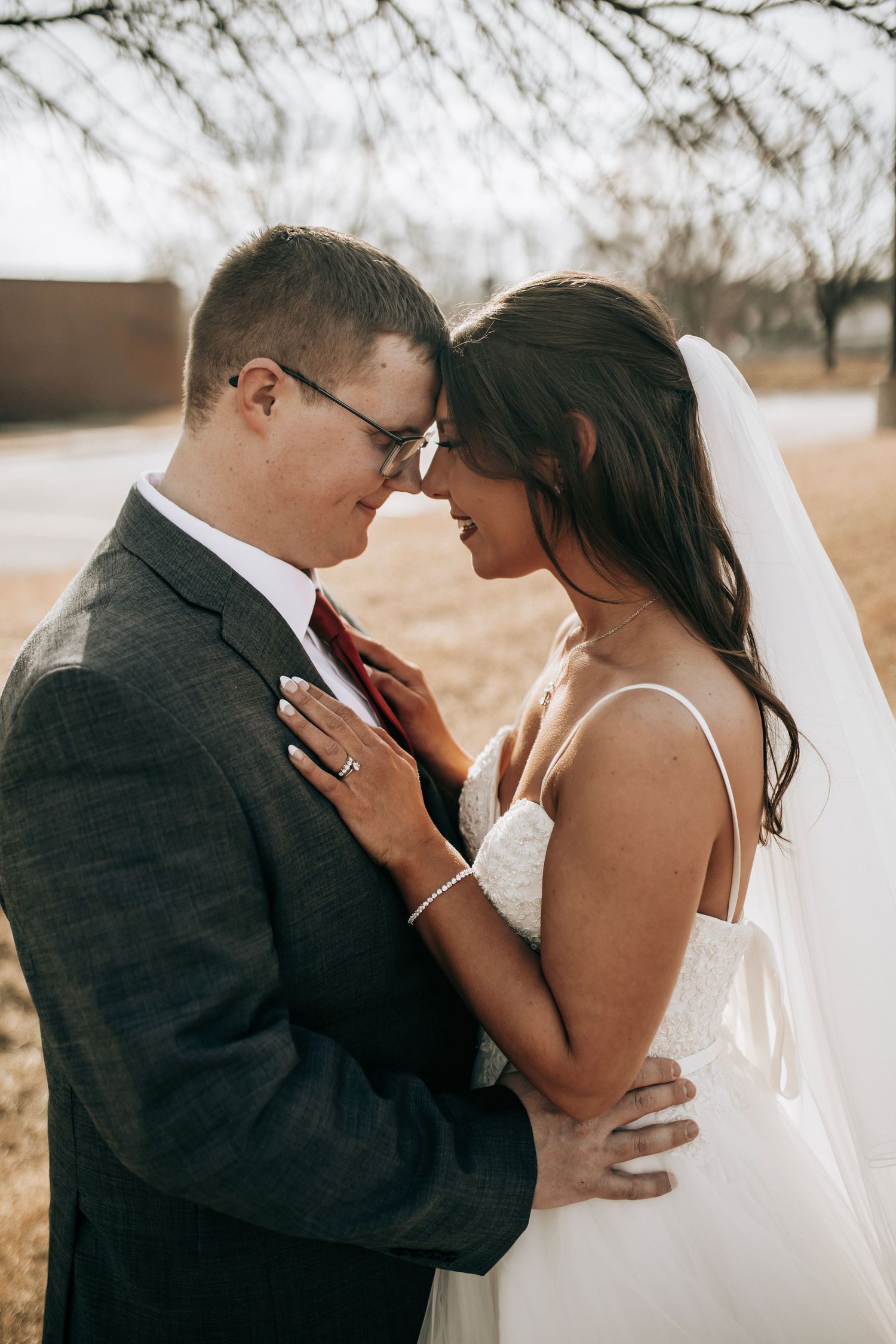 A romantic wedding photo series showing tender moments between newlyweds against a muted winter landscape.