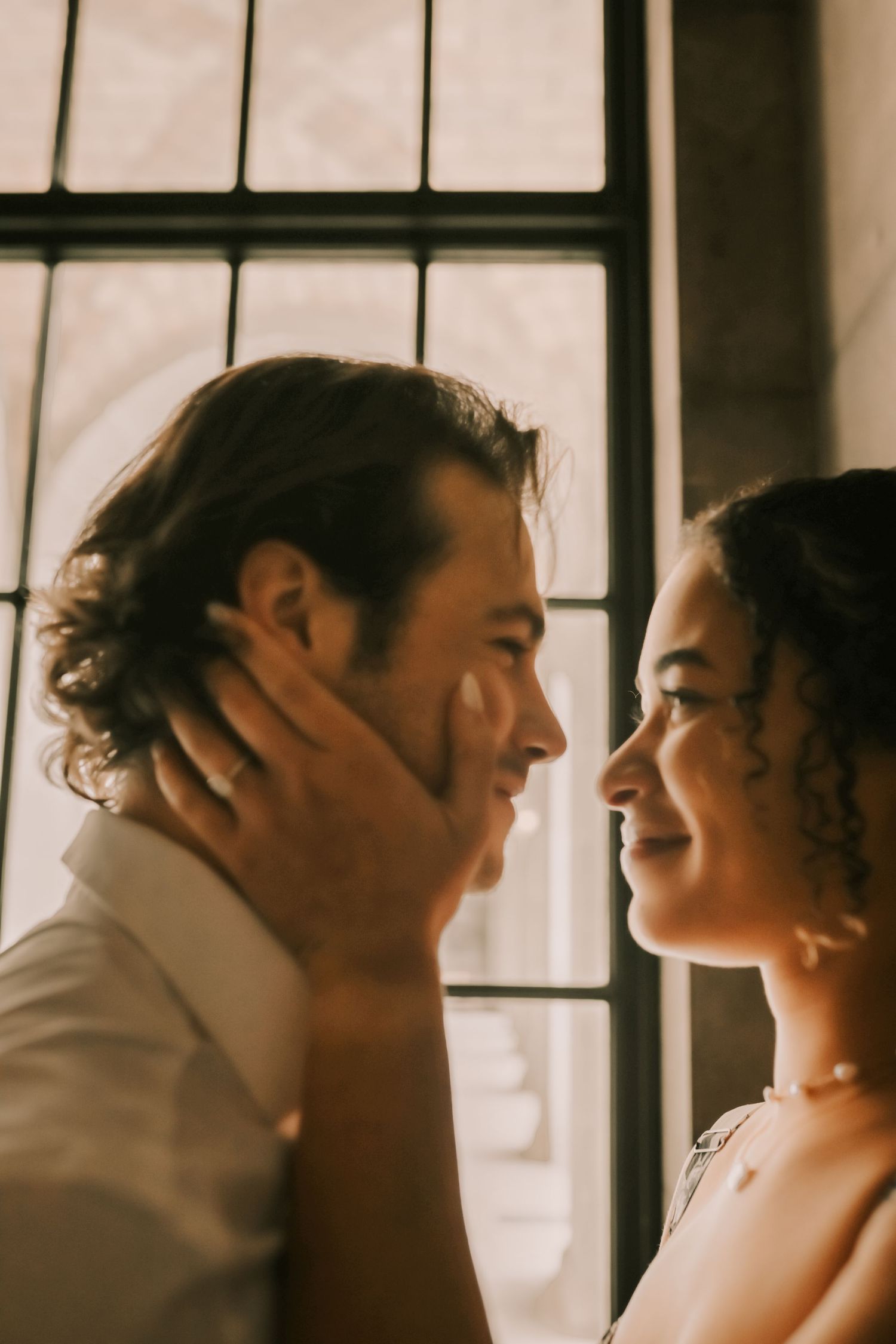 A romantic sepia-toned photo series showing an intimate couple in vintage window light.