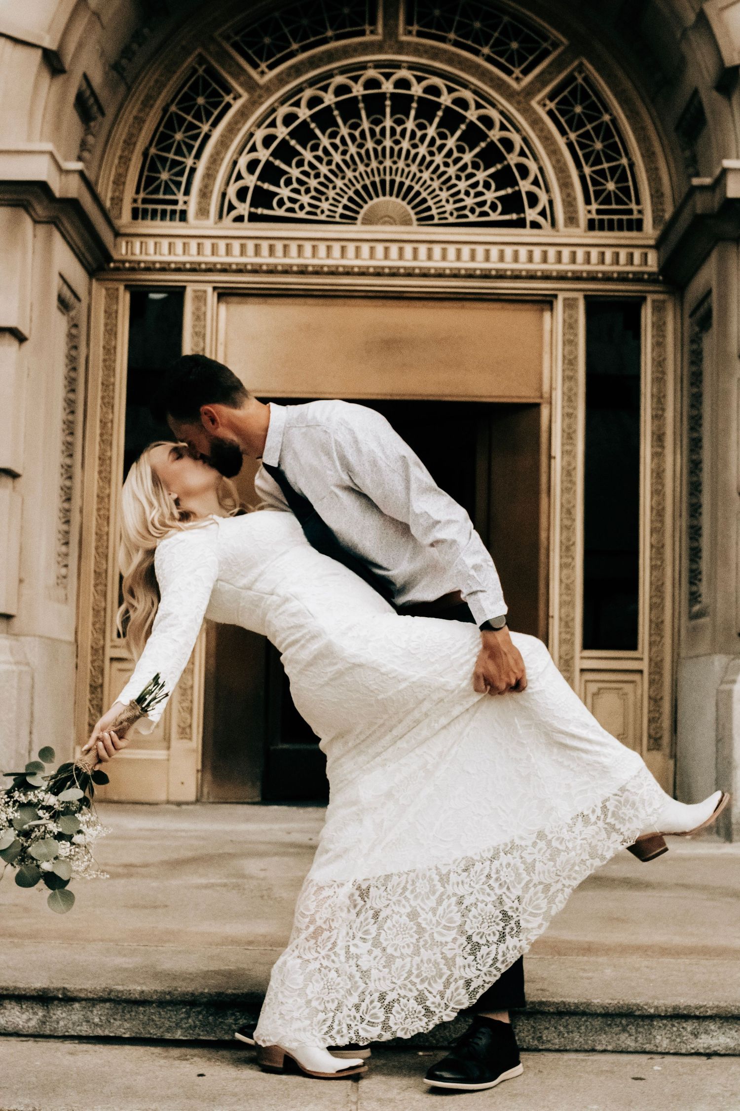 A romantic dip pose on elegant stone steps with ornate architectural details.