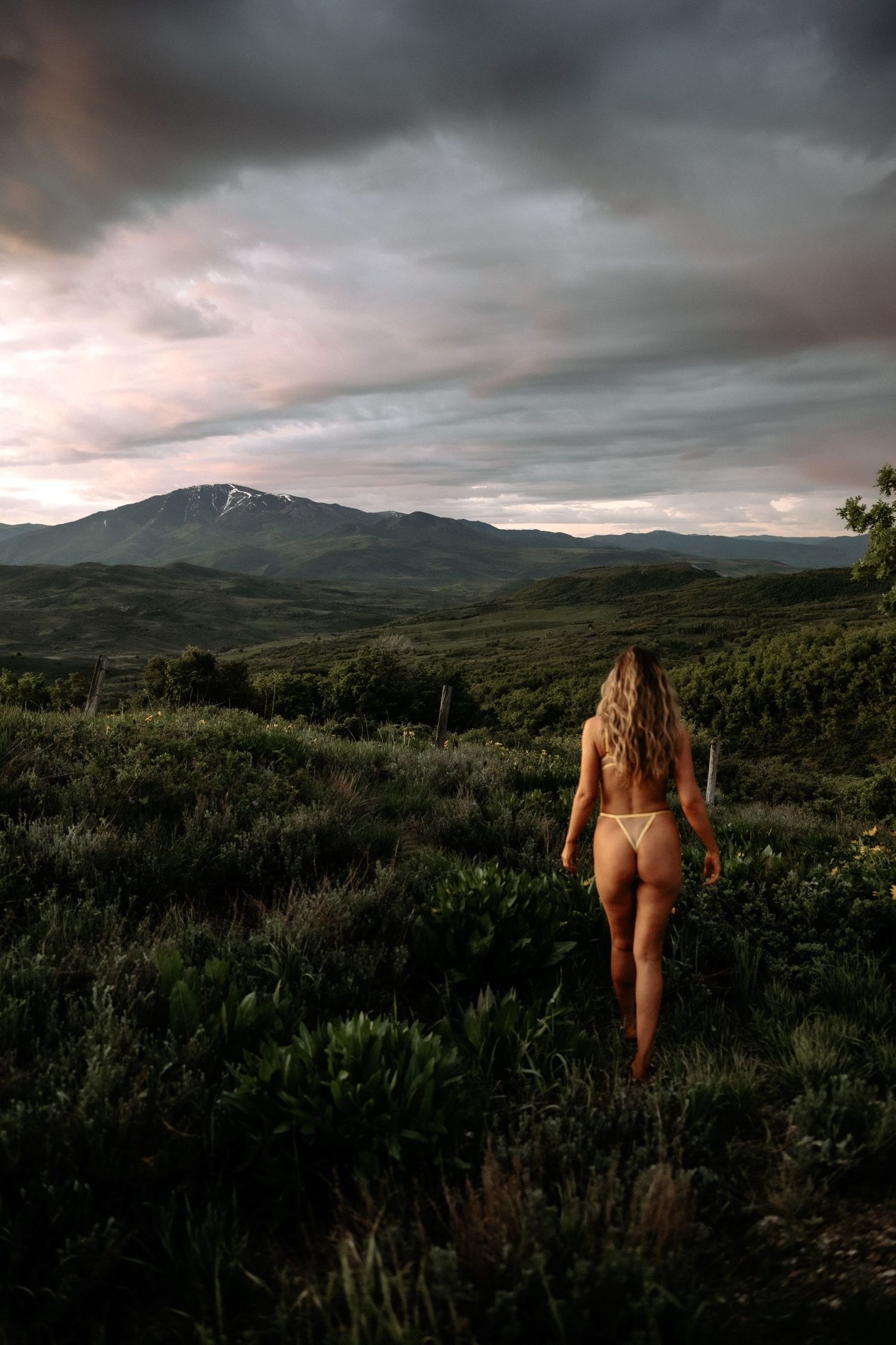 Outdoor Boudoir Photo of woman posing in Utah with red sky and wild flowers.