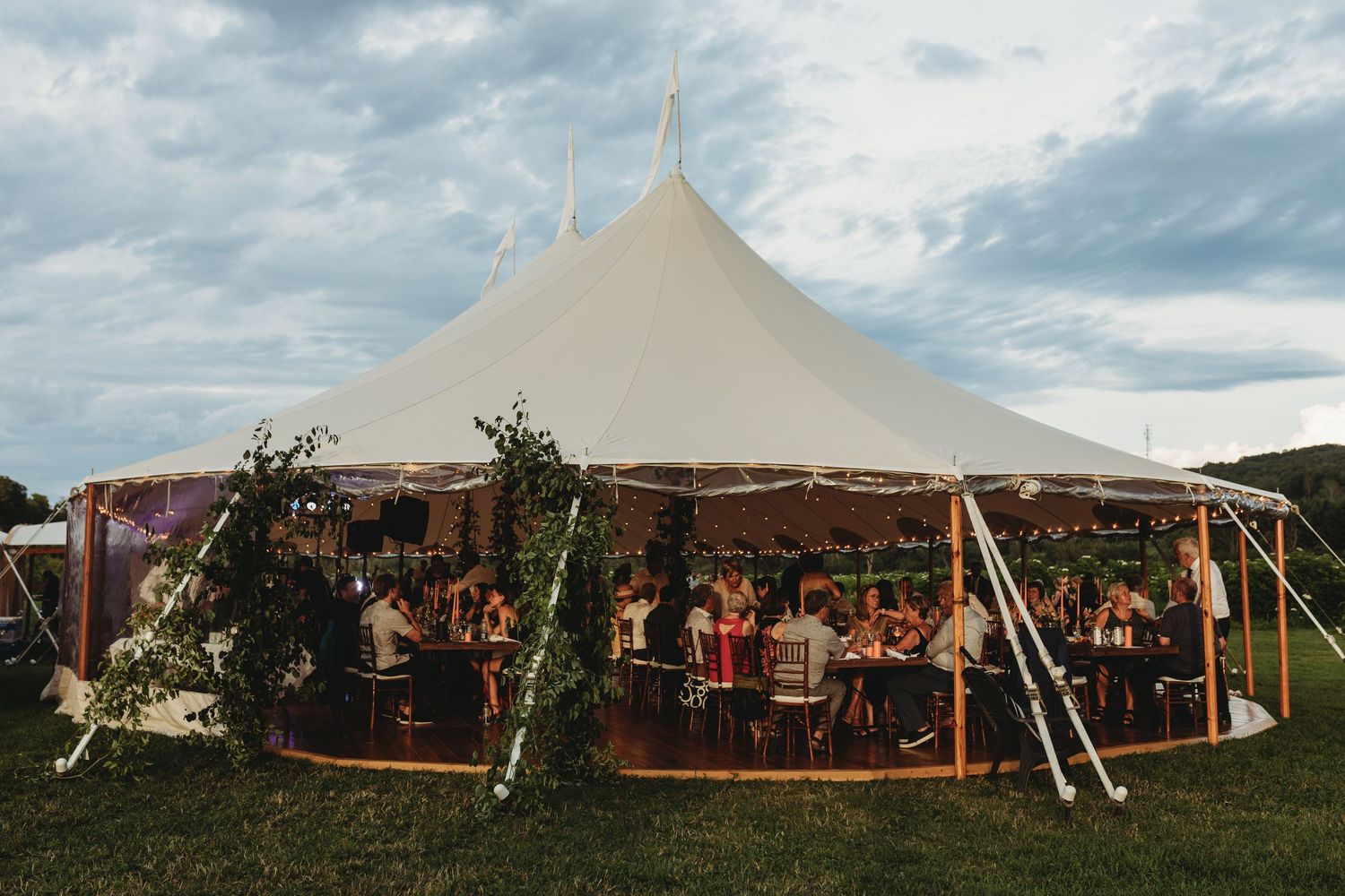 Large white event tents set up outdoors against a cloudy sky for a gathering or festival.