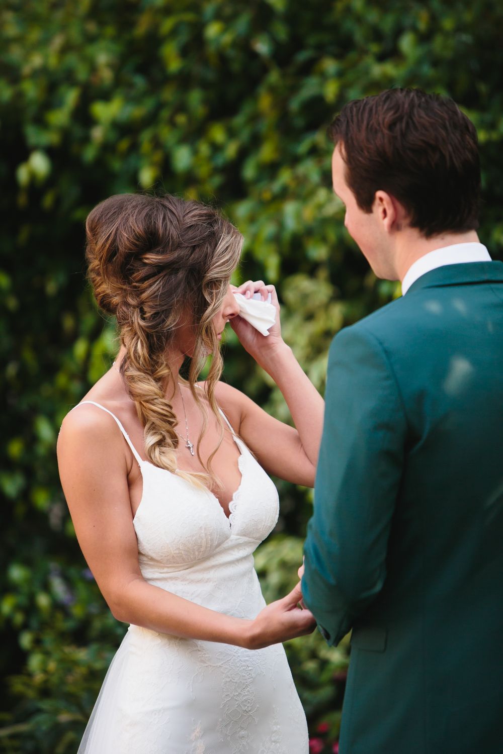 Intimate wedding moment captured in a garden setting with a white dress and dark suit.
