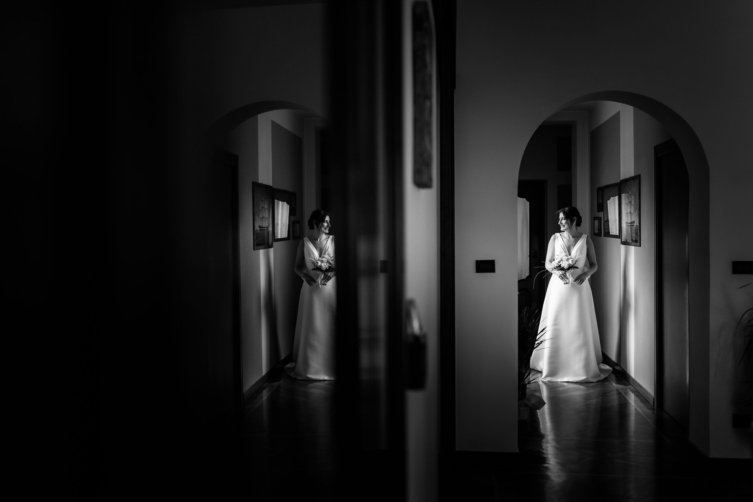 A ghostly figure in white stands at the end of a dark, eerie hallway creating an unsettling atmosphere.
