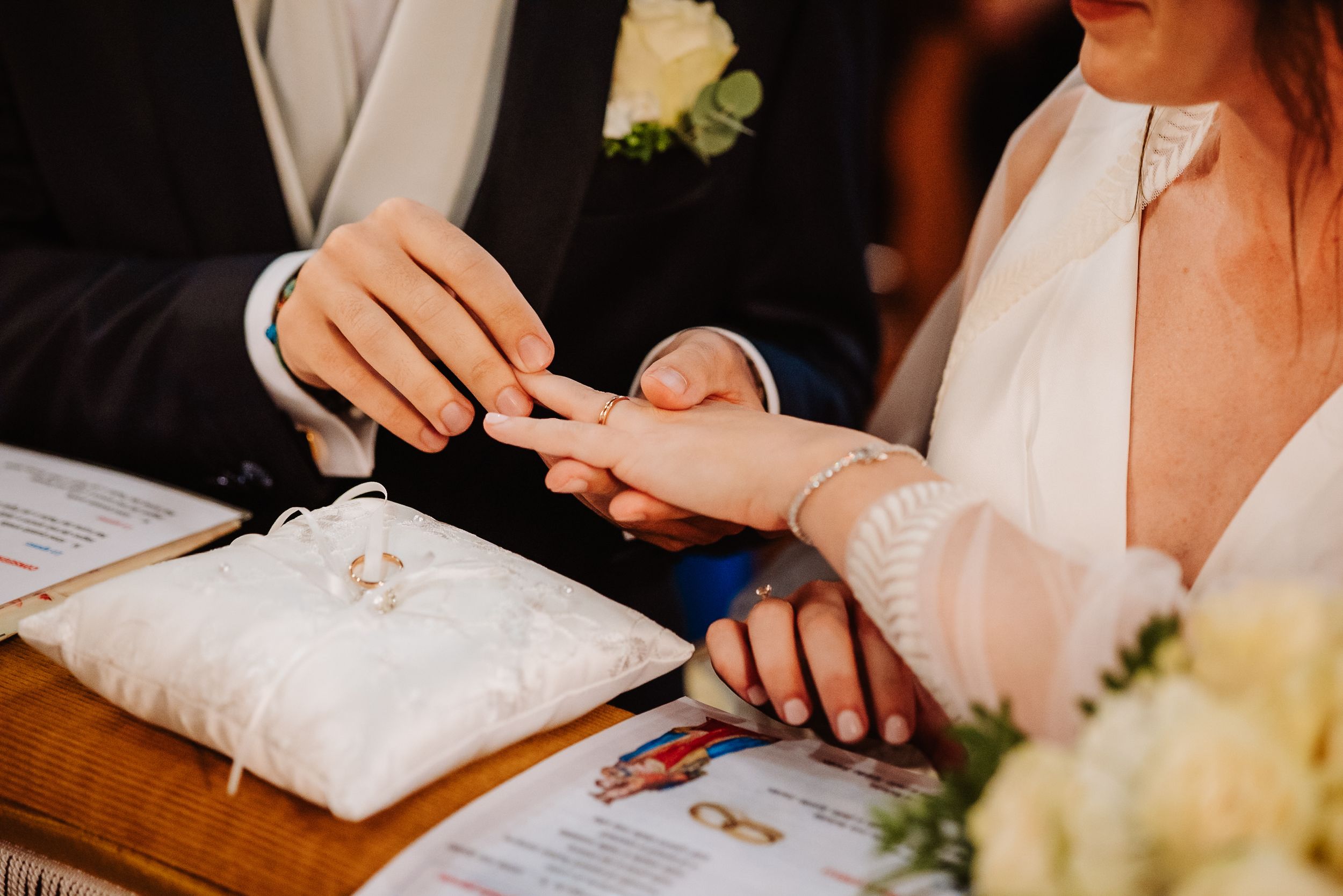 Close-up shots of hands signing a wedding registry book with elegant white decor and floral accents.