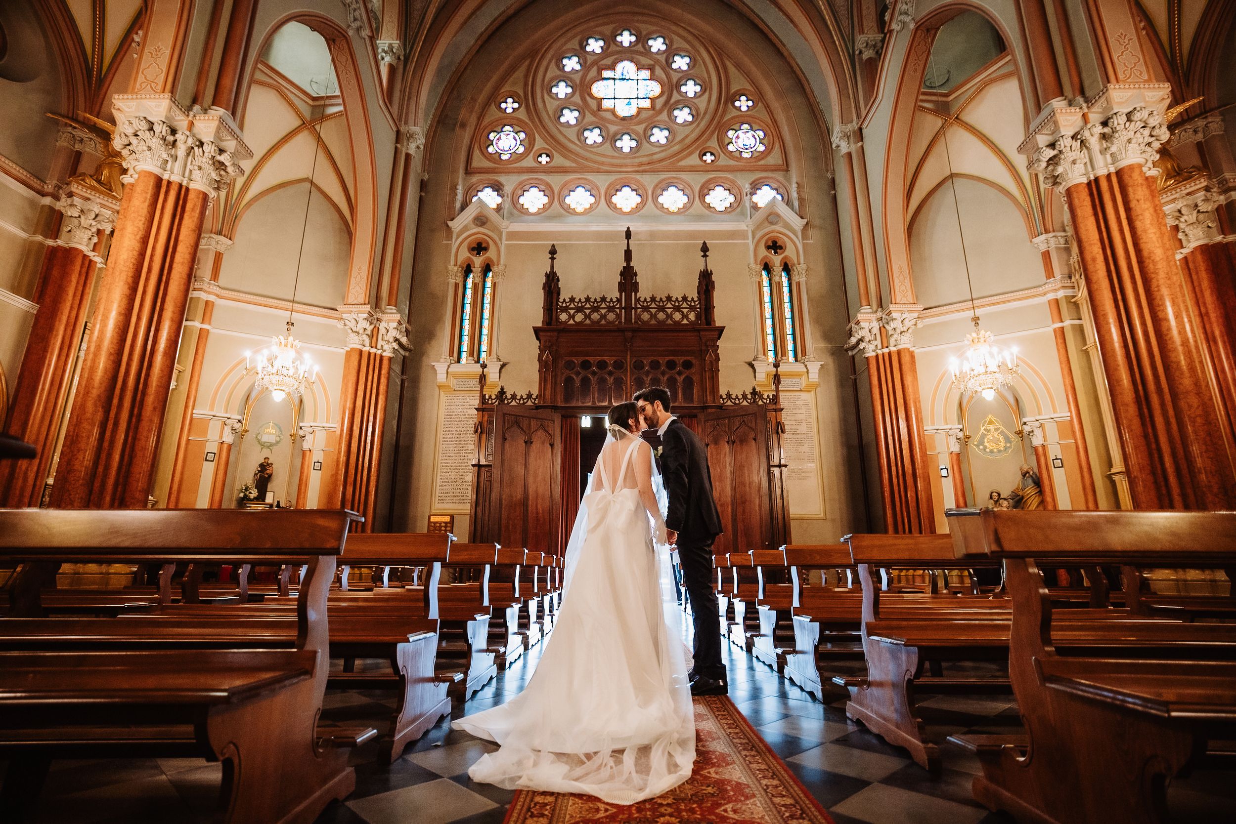 Elegant wedding photos in a grand cathedral with gothic architecture, ornate stained glass windows, and warm lighting.