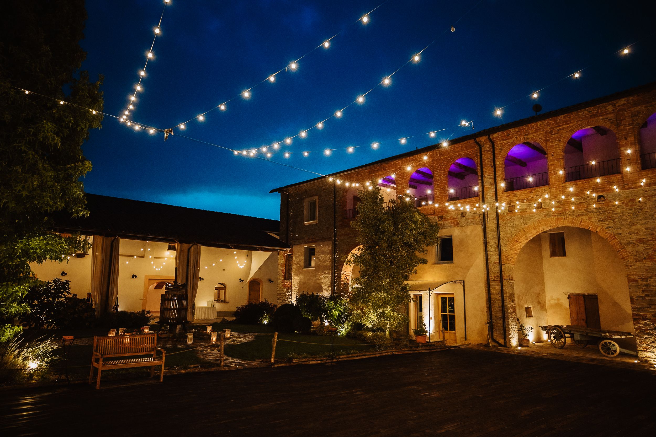 String lights illuminate the exterior of adobe buildings at dusk creating a warm and inviting atmosphere.