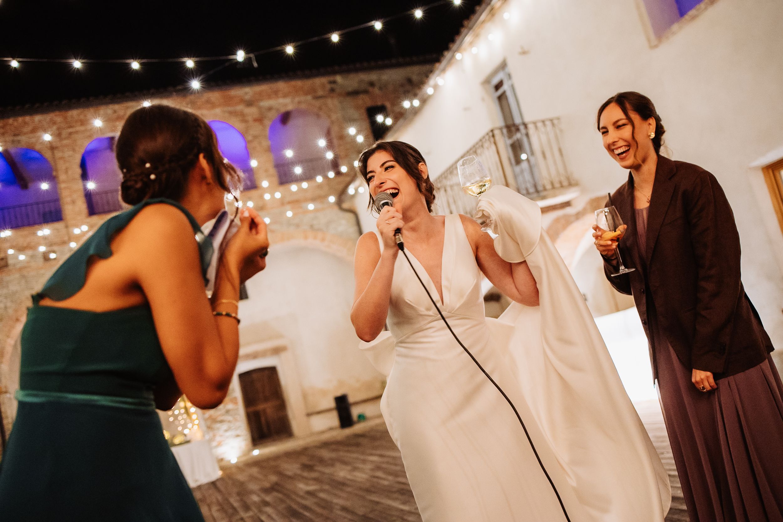 Wedding reception guests dancing and celebrating under warm string lights and decorative lighting.