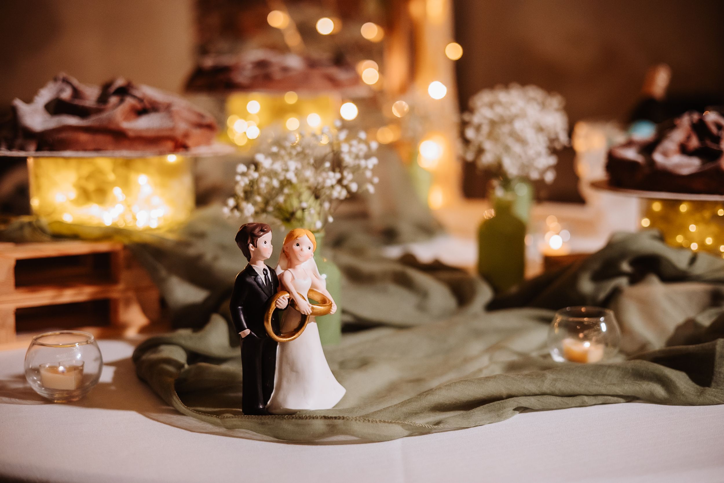 Wedding reception table settings with elegant candlelight and floral centerpieces on sage green linens.
