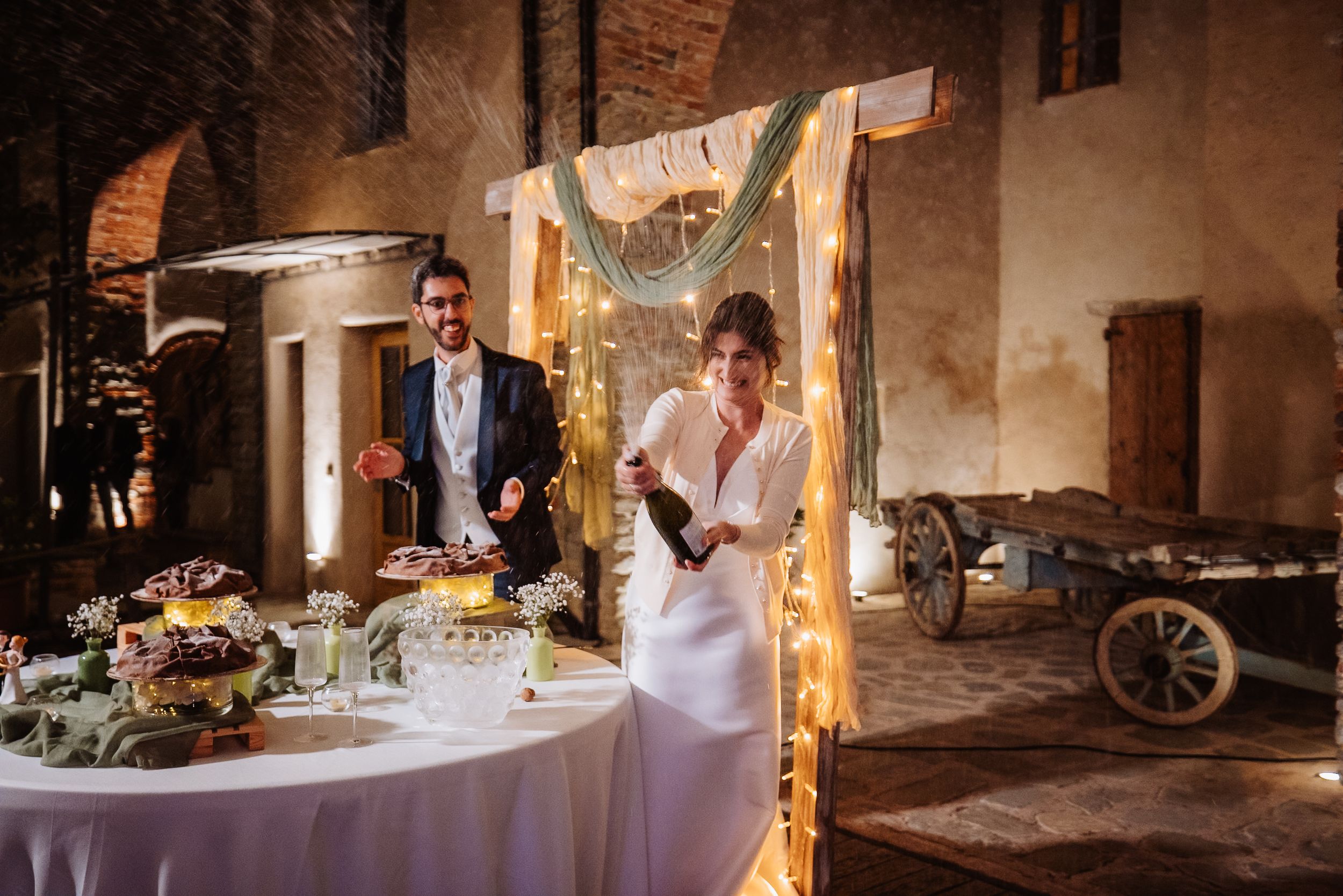 Elegant rustic wedding reception setup with decorated table and string lights in an old stone building.