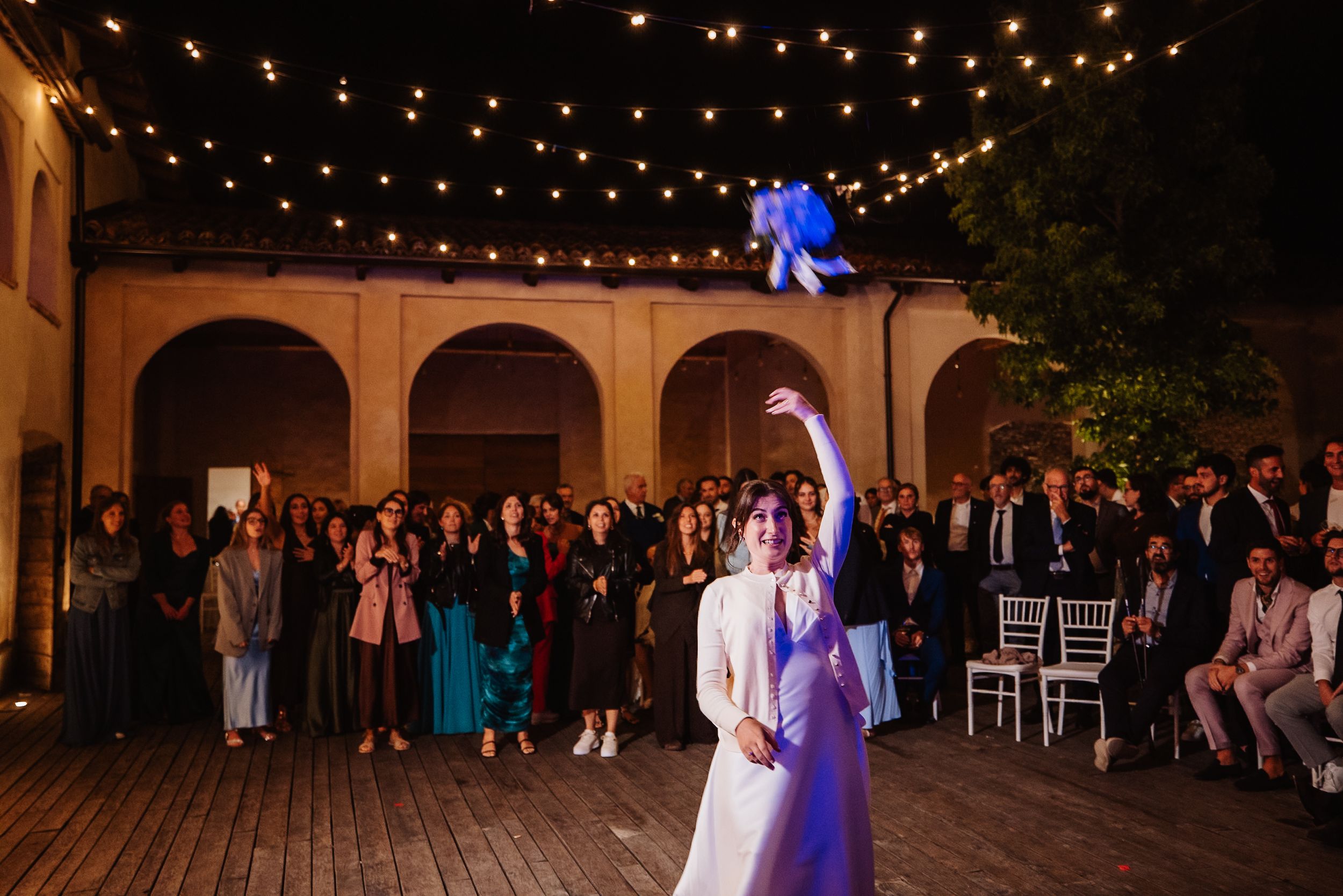 Wedding reception venue with string lights creating a magical atmosphere under covered outdoor space.