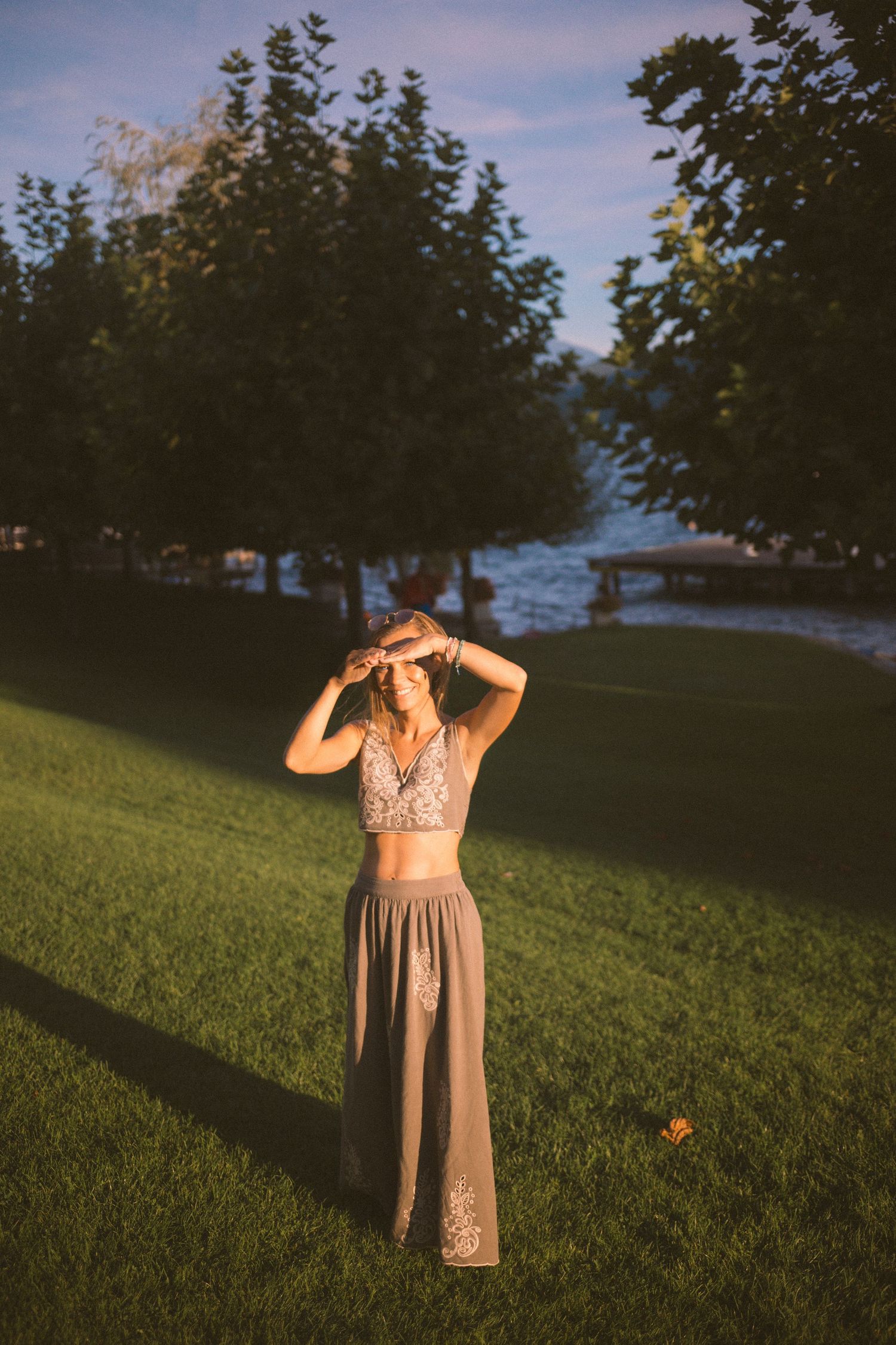 A series of photos showing a figure in a flowing dress standing on a grassy hill at sunset.